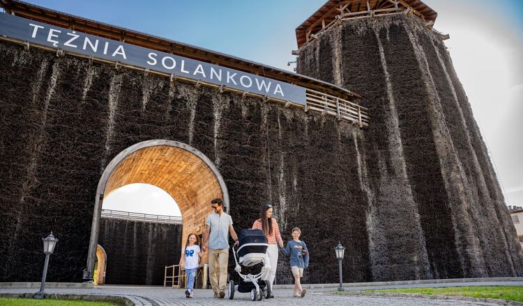 Tężnia solankowa, widok na spacerującą obok tęzni rodzinę.
